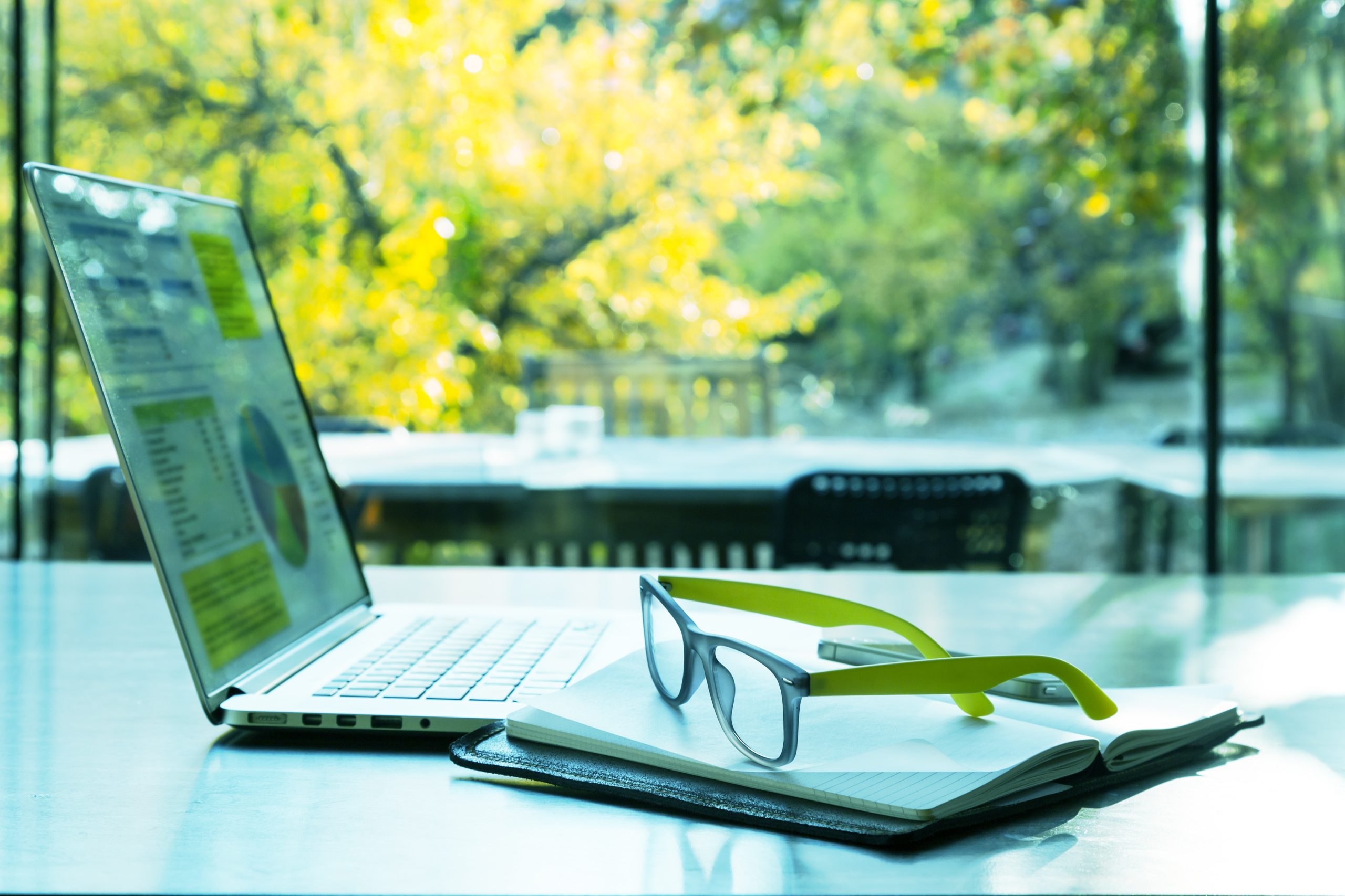 computer and glasses in office surrounded by outdoors - sustainability in 2023