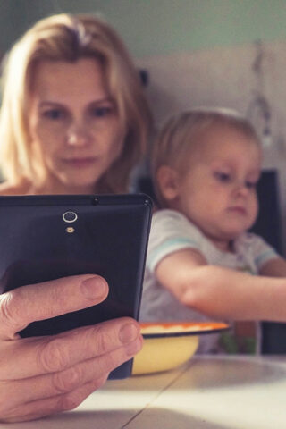 women and children at table with phone - The digital divide