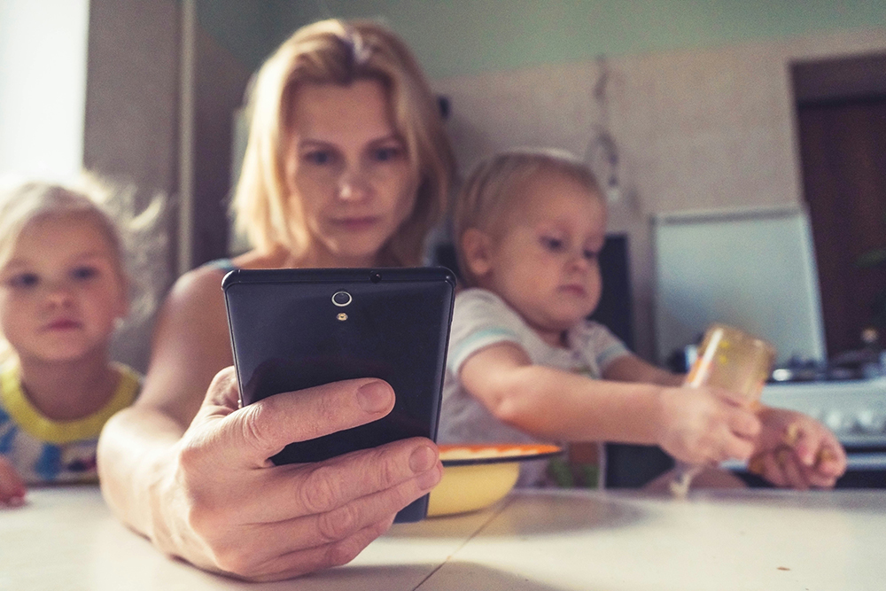 women and children at table with phone - The digital divide