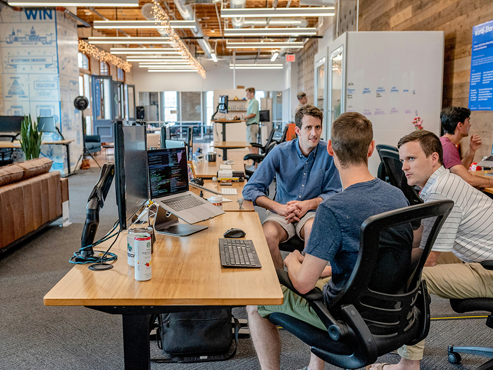 Group of men around desk - IT Sustainability
