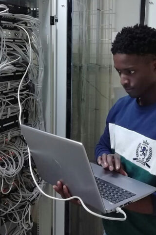 man on laptop in front of server station - sustainability
