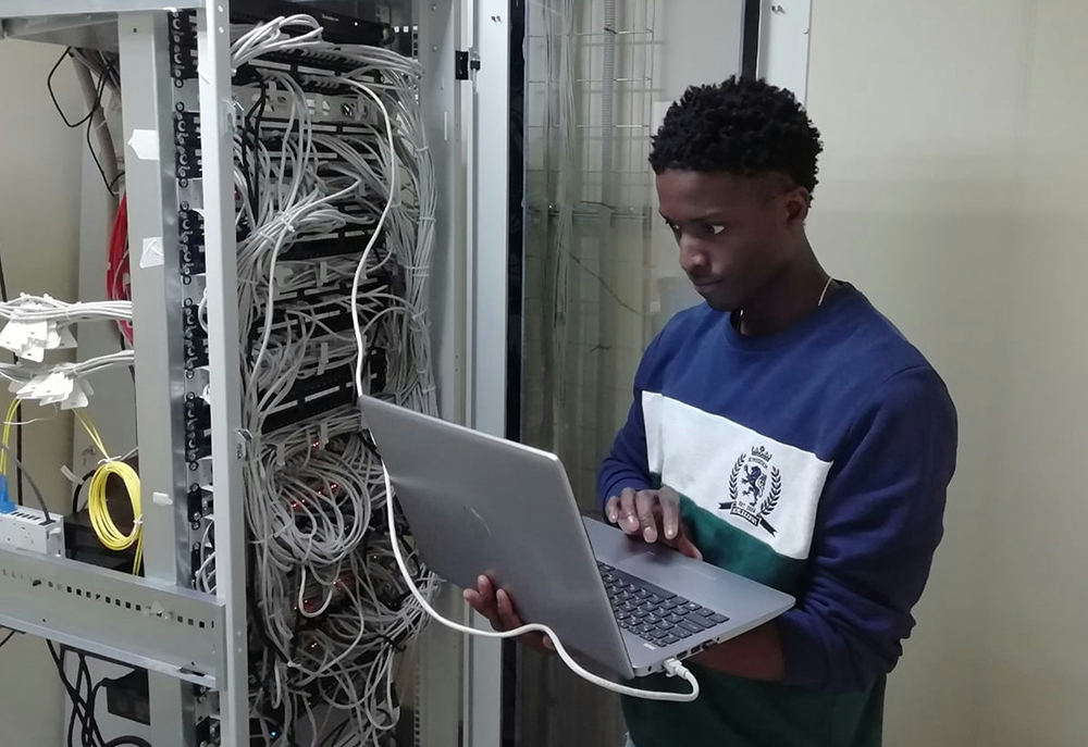 man on laptop in front of server station - sustainability
